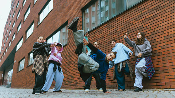 istock Breakdance crew performing power moves near brick wall. 2255872362