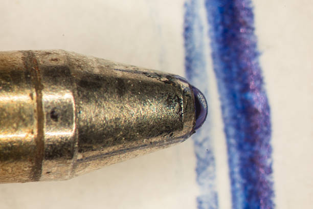 Ballpoint pen refill with ink ball writes on paper very close up
