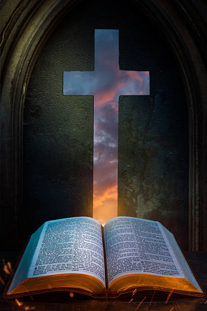 An open Bible sits beneath a glowing cross-shaped window showing a sunset sky, symbolizing divine inspiration, hope, and faith.