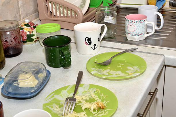 There are dirty dishes on the table in the kitchen near the sink.