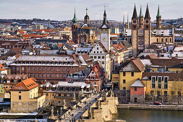 Wuerzburg, Germany - January 03, 2026: Pedestrians on the old Main bridge in winter. In the background, the towers of St. Kilian's Cathedral.