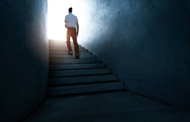 istock Man climbing stairs toward bright light 2255892454