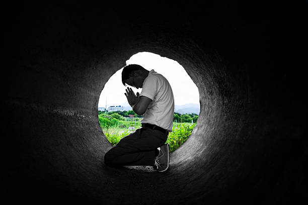 Side view a man praying in a dark tunnel near nature