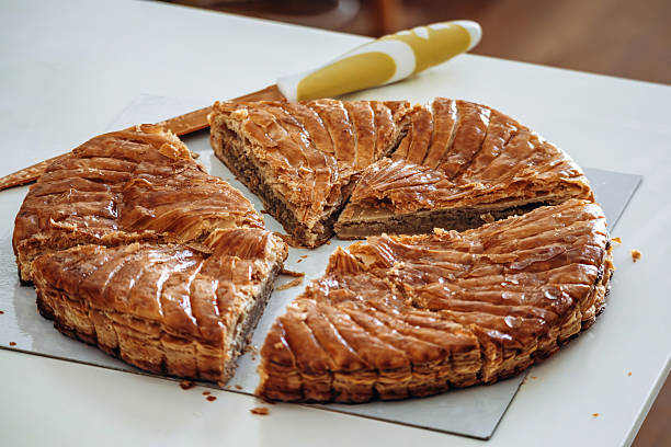 Sliced galette des rois displayed on a white surface, a traditional French puff pastry cake with almond filling served during Epiphany celebrations