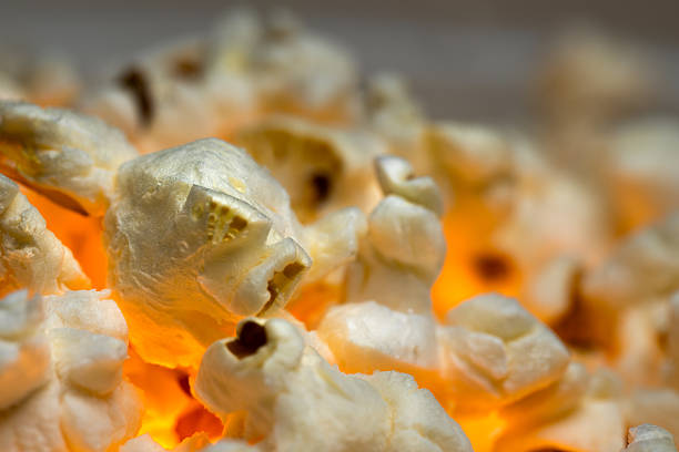 A close-up shot of popcorn with a warm, orange glow emanating from within, suggesting it is freshly popped and still hot.