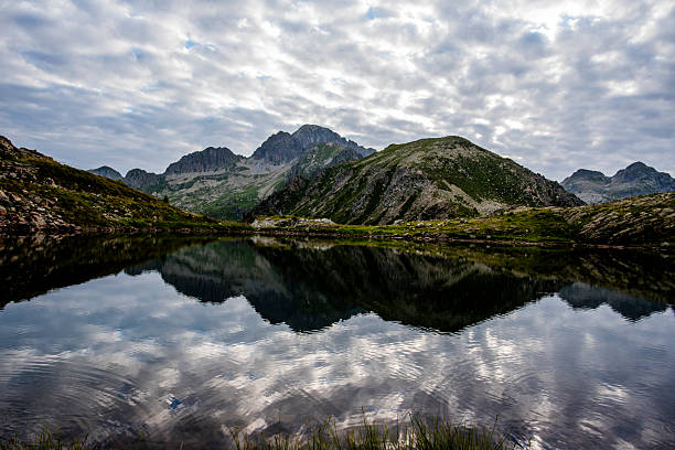 Alpine lake reflecting rugged peaks and soft clouds under dramatic light, captured in the Lagorai mountains of northern Italy