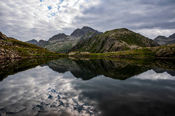 Still alpine lake mirroring dark clouds and steep rocky peaks, photographed in the Lagorai mountains of northern Italy.