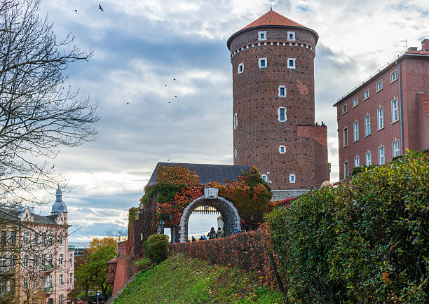 Krakow, Poland – October 25, 2025: The medieval Florian Gate tower rises above a stone archway covered in autumn ivy, as visitors walk beneath the historic entrance leading toward Krakow Old Town.