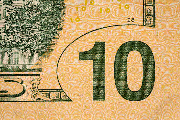 A close-up of a ten dollar bill shows the number ten and some design patterns. The bill has intricate features and colors. It captures currency details and texture.