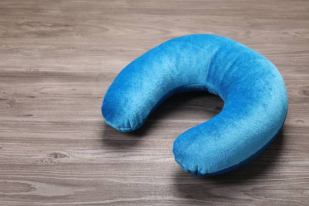 Light blue travel pillow on wooden table, space for text