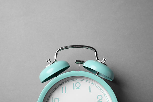 Turquoise alarm clock on grey background, top view