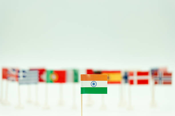 Many small flags from various countries are arranged with the Indian flag in front. The display shows diversity during an event. The setting is bright and simple.
