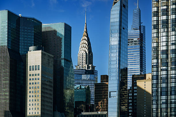 A vibrant Manhattan skyline featuring glass towers and the iconic Chrysler Building, capturing urban density, modern architecture, and the energy of New York City on a clear blue day.