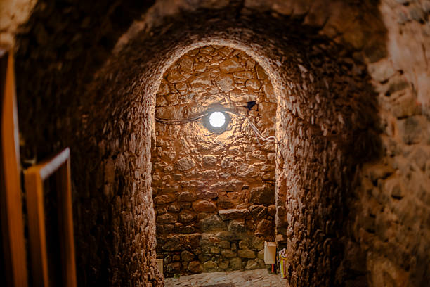 Stone arched corridor inside a traditional Corsican village building. Rustic masonry, warm light, historic interior passage, medieval architecture, European heritage travel concept.