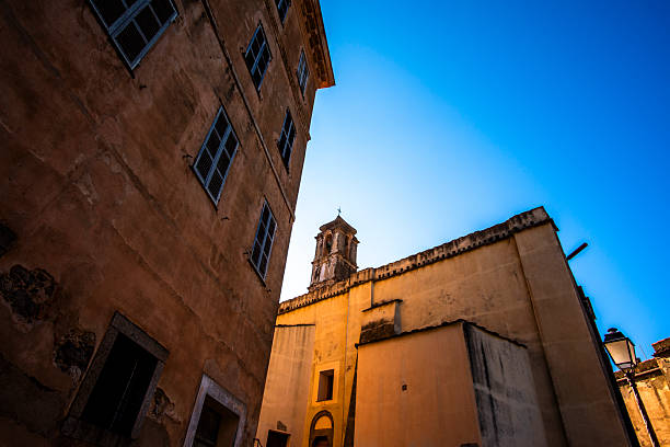 Minimalist view of a Mediterranean building corner in Corsica, France, with pastel facade, shuttered windows and intense blue sky. Southern European urban atmosphere.
