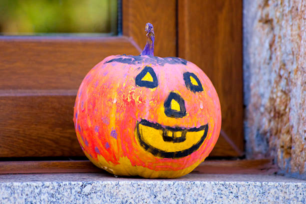 Painted Jack-o-Lantern Pumpkin figurine close-up view on window sill. Galicia, Spain. Monster shape, scary.