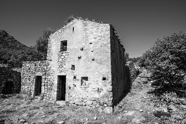 Black and white view of abandoned rural stone house in Corsica France. Stark geometry and rough surfaces emphasize decay, memory and resilience in a timeless countryside setting.