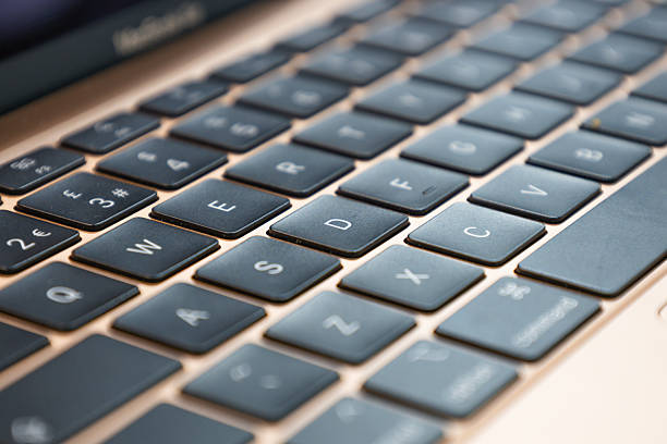 Detailed close-up of a modern laptop keyboard featuring black keys on a metallic rose gold surface. London, UK, 17 March 2024