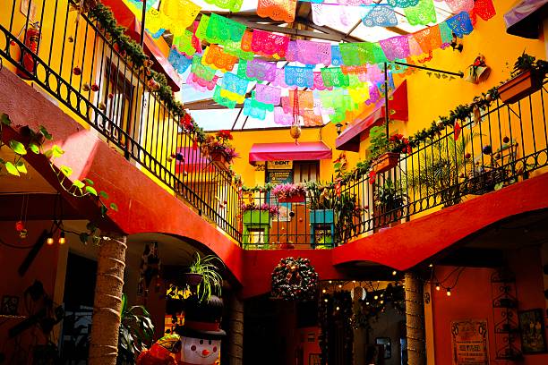 Mexico City, CDMX, Mexico – December 28, 2025: A bright interior courtyard with balconies and papel picado is decorated with holiday ornaments and lights.