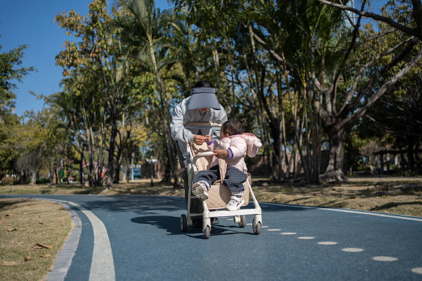 In the park, a mother is pushing a baby stroller