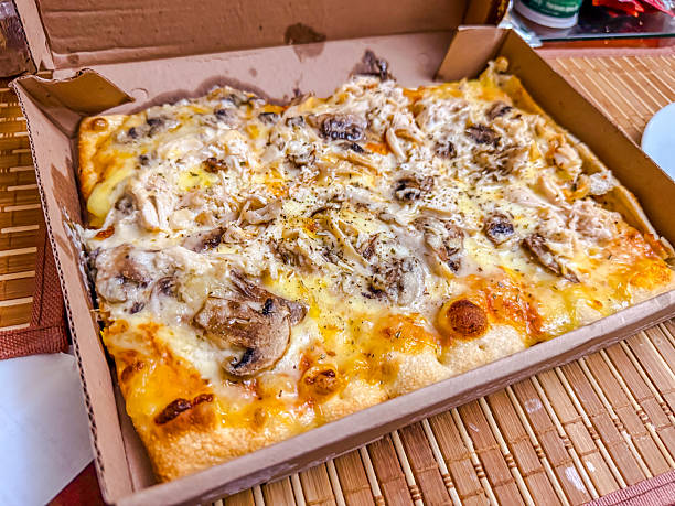 Rectangular chicken and mushroom pizza with melted cheese in cardboard box