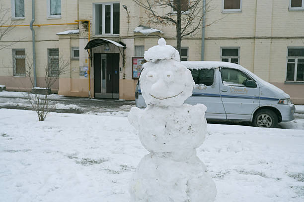 Snowman in Urban Setting with Building in Background