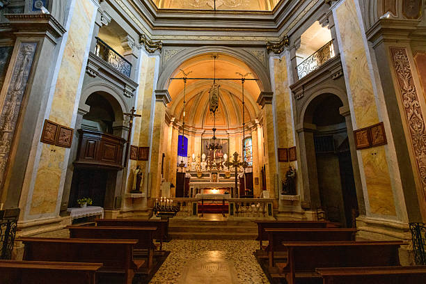 Warm light fills the ornate nave of a historic church on Isola Bella, featuring marble columns, wooden pews, and an elaborate altar with religious statues and stained glass. The architecture blends classical elements and intricate detailing, creating a serene and reverent atmosphere.