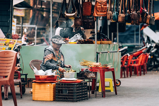 Hoi An, Vietnam - May, 11, 2024: Woman selling food on the streets of Hoi An. Street food is part of the Vietnamese culture. You can find food stalls selling a variety of fresh food all over Vietnam.