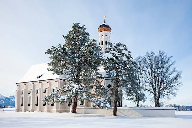 A winter scene with a beautifull small St. Coloman's church and trees in snow under blue sky in Schwangau, Allgau, Bavaria, Germany
