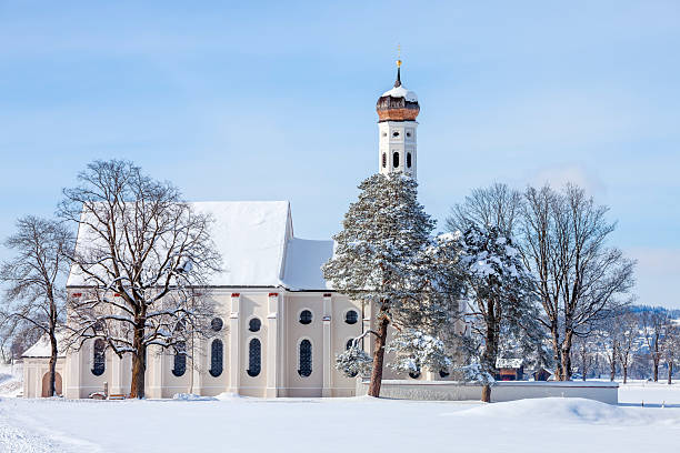 A winter scene with a beautifull small St. Coloman's church and trees in snow under blue sky in Schwangau, Allgau, Bavaria, Germany