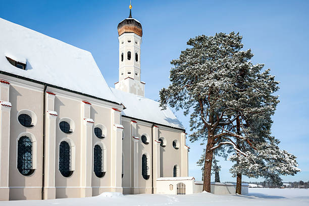 A winter scene with a beautifull small St. Coloman's church and trees in snow under blue sky in Schwangau, Allgau, Bavaria, Germany
