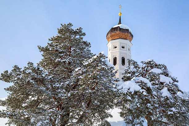 A winter scene with a beautifull small St. Coloman's church and trees in snow under blue sky in Schwangau, Allgau, Bavaria, Germany