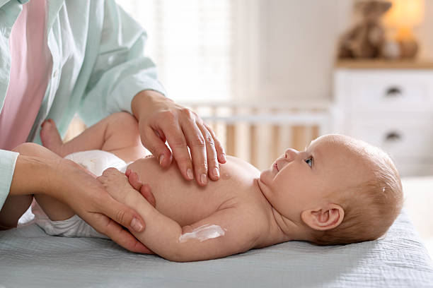 istock Mother applying cream onto her baby's arm on changing table at home, closeup 2255966645