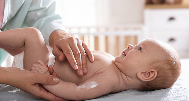 istock Mother applying cream onto her baby's arm on changing table at home, closeup 2255967506
