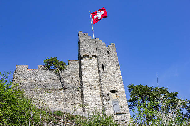 Basel, Switzerland - April 01. 2017: Castle Stein ruins built on a rocky promontory with a Swiss national flag above Baden gorge. It is a Swiss heritage site of national significance.