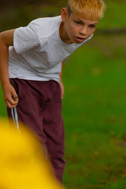 Boy surprises outdoors, Boy leaning forward with astonished expression in grassy outdoor setting, Young boy gazes intensely with surprise in dewy grass during outdoor activity