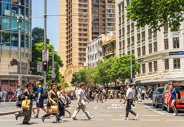 Sydney, Australia - People crossing the street in bright sunshine on the corner of George Street and Park Street in central Sydney.