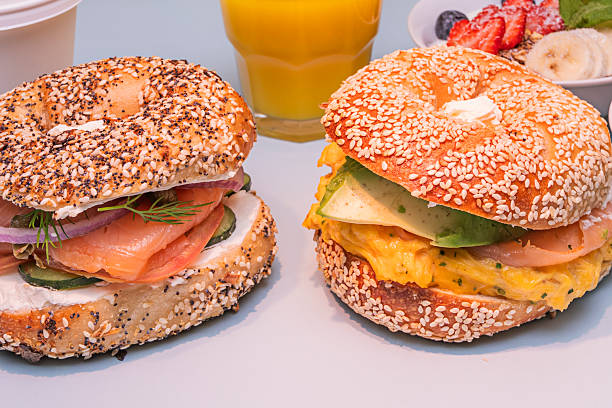 A whole-wheat bagel, open and generously spread with cream cheese, topped with thin slices of smoked salmon, garnished with capers, red onion rings, and a touch of fresh dill.