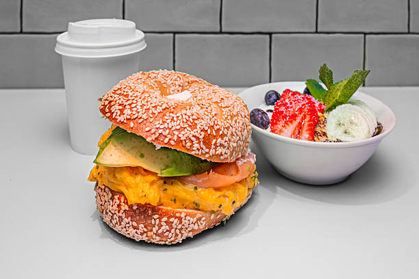 a freshly toasted sesame bagel serves as the base for a mountain of pink salmon, crisp arugula, and a dill sauce that drips down the sides, inviting the first bite.