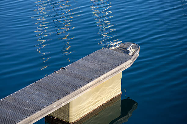 Marina dock extending over calm blue water with sunlight reflections