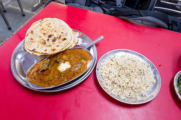 Paneer curry with naan and rice on red table Delhi