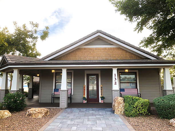 Kingman, AZ - November 11, 2025: A charming retro bungalow with a large porch and US flags in central Kingman; the town is located on historic Route 66.