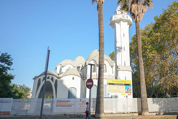 A white building with a red sign on it. A person is standing in front of the building