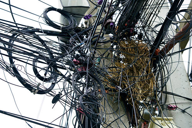 A detailed view of a power pole showcasing tangled wires intertwined with a nest, highlighting the interaction between urban infrastructure and wildlife.