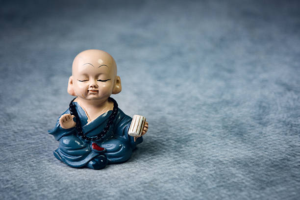 Peaceful monk figurine meditating on textured background