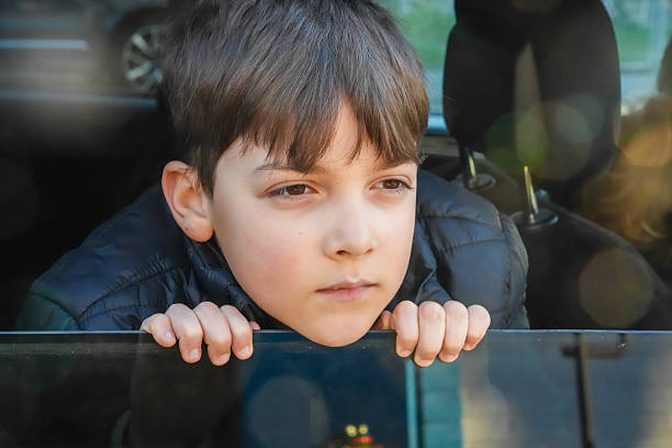 Serious little boy looking though a vehicle window