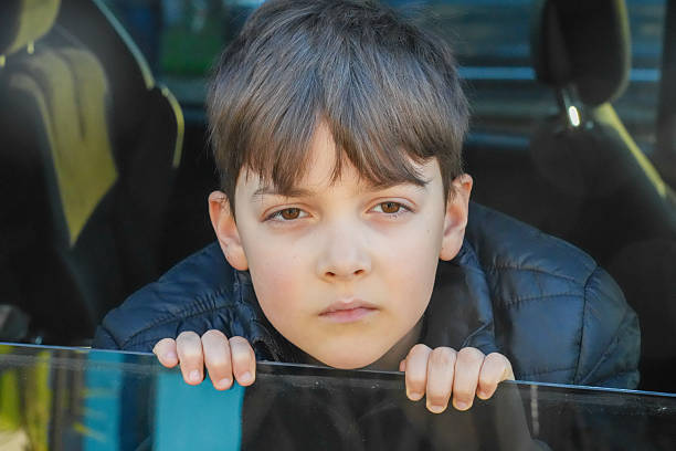 Serious little boy looking though a vehicle window