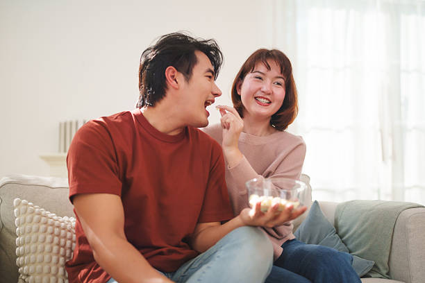 istock Asian young couple feeding popcorn together at home 2255999935