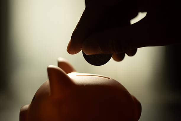 Putting Coins into Piggy Bank for Saving Money Concept.