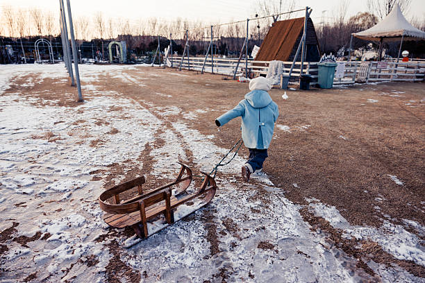 A happy little boy pulled a sled and ran on the snow
